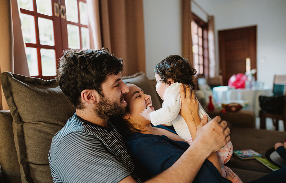 Mother and Father sitting on the couch with their baby