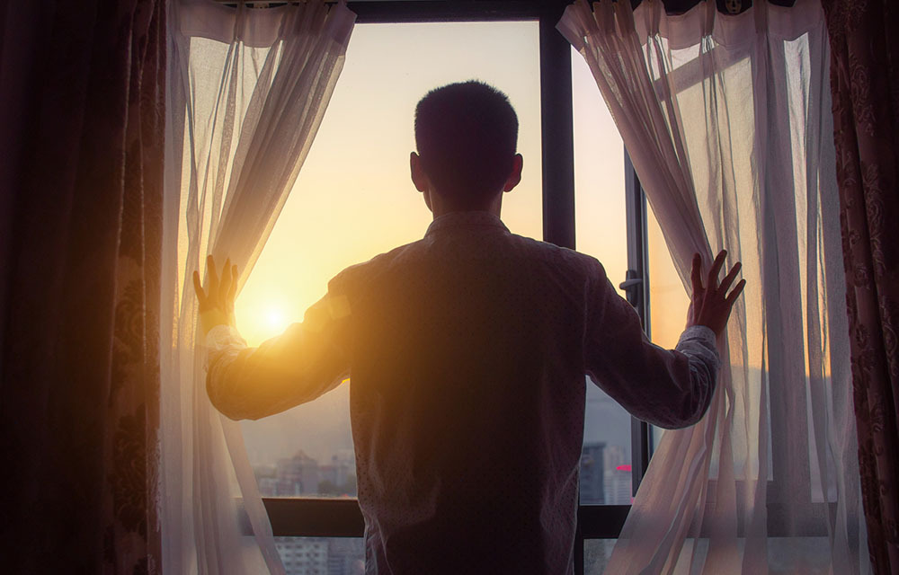 Person looking at sunrise through window