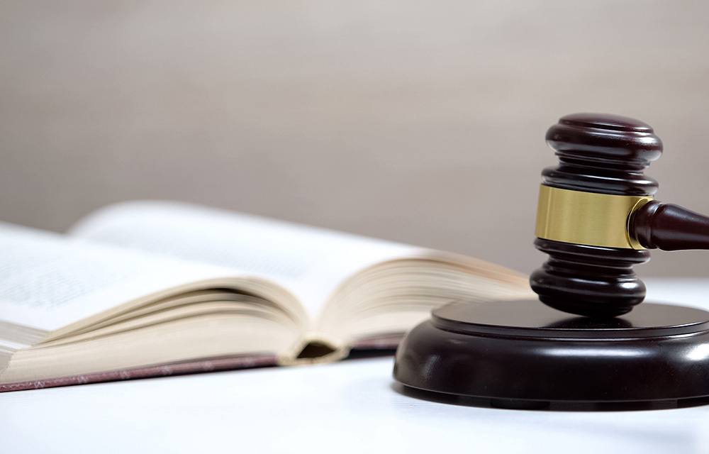 Gavel sitting next to an open book on a white table surface