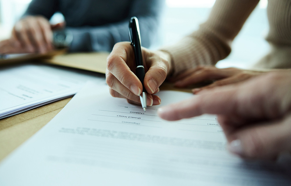 Stock photo of someone signing a document with a pen