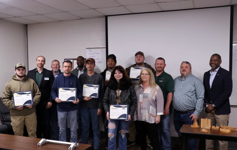 Class of community college students posing with their earned certificates.