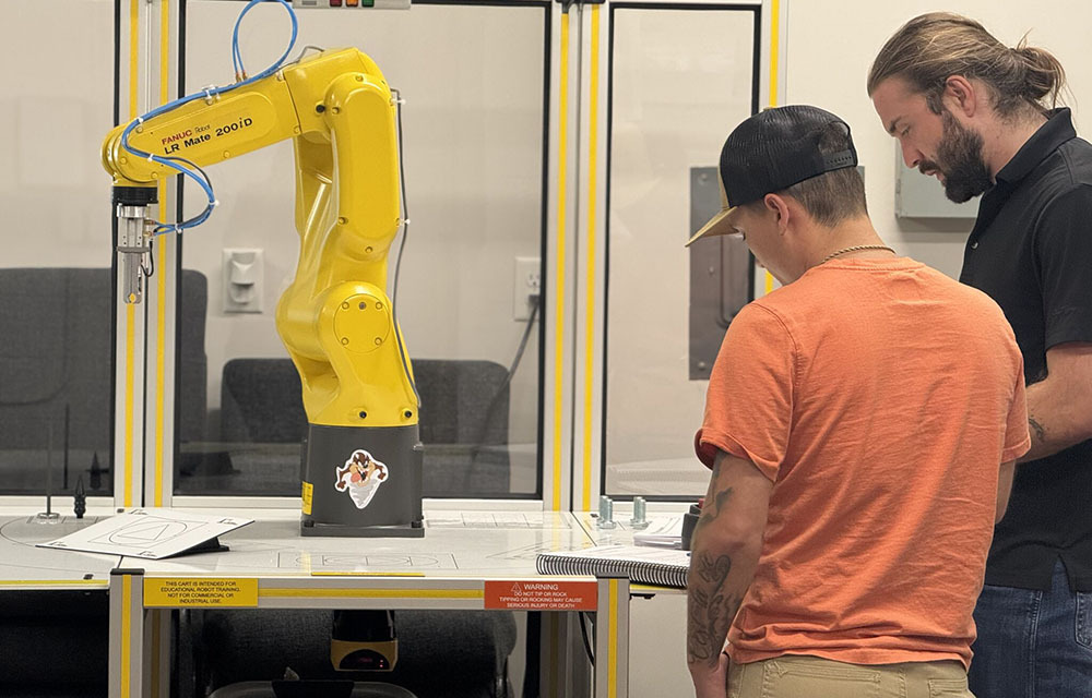 Instructor showing student how to use a robotic arm.