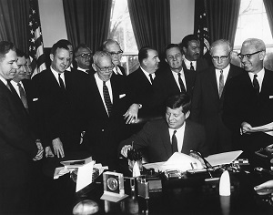 John F Kennedy signing bill with his colleagues standing around him