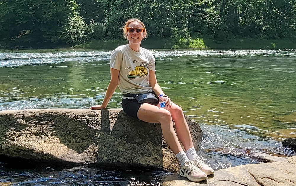 Maggie Blume sitting on rock with a river behind her