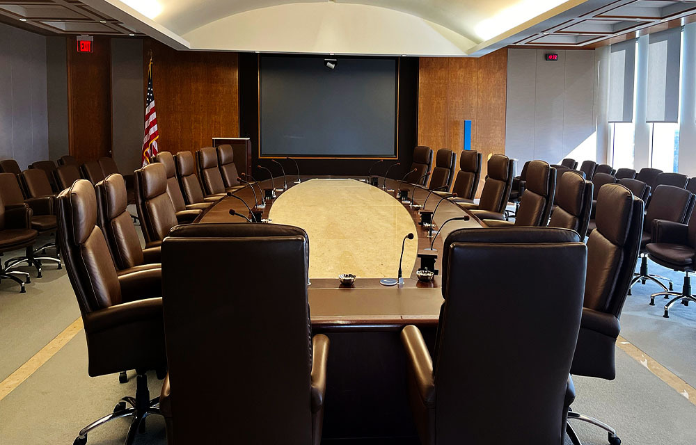 Federal Reserve meeting room with leather chairs surrounding long table.