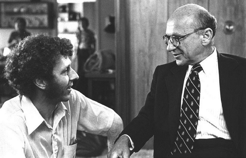 Robert Chitester kneeling down beside Milton Friedman for a pleasant conversation.