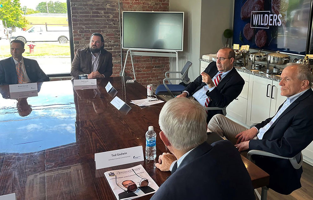 Tom Barkin and various business leaders sitting and talking around a wooden roundtable.