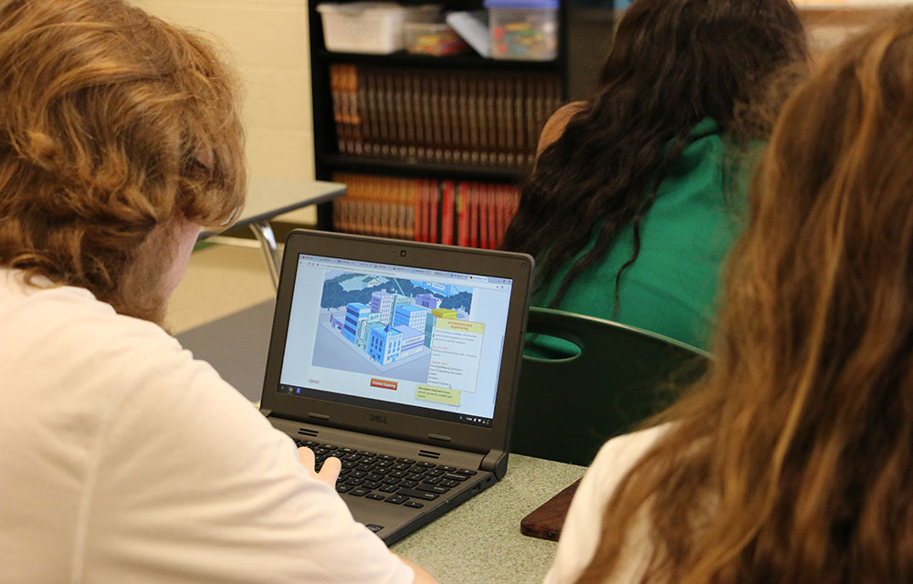 Students exploring a module from the Invest in What's Next module on their laptop.