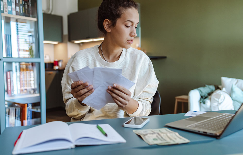 Woman sorting through envelopes in front of her computer.