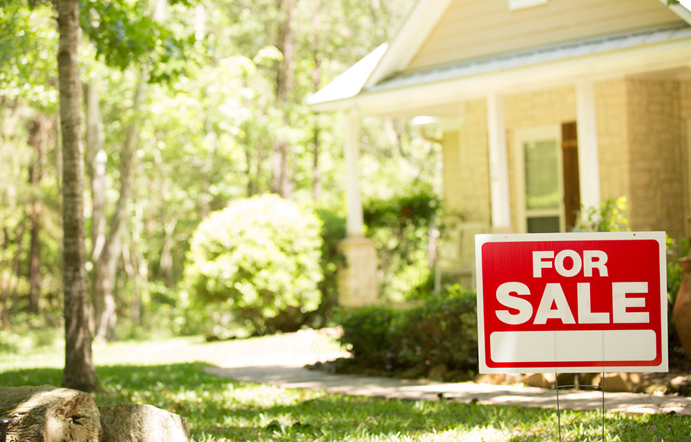 For sale sign sitting in front of house