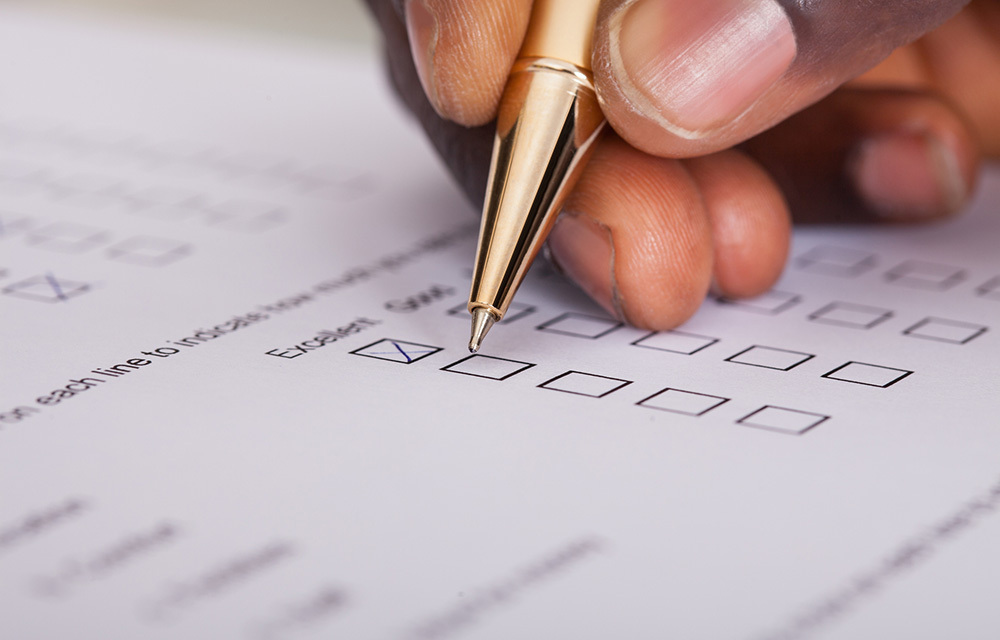 Close up of hand filling out survey with a pen.