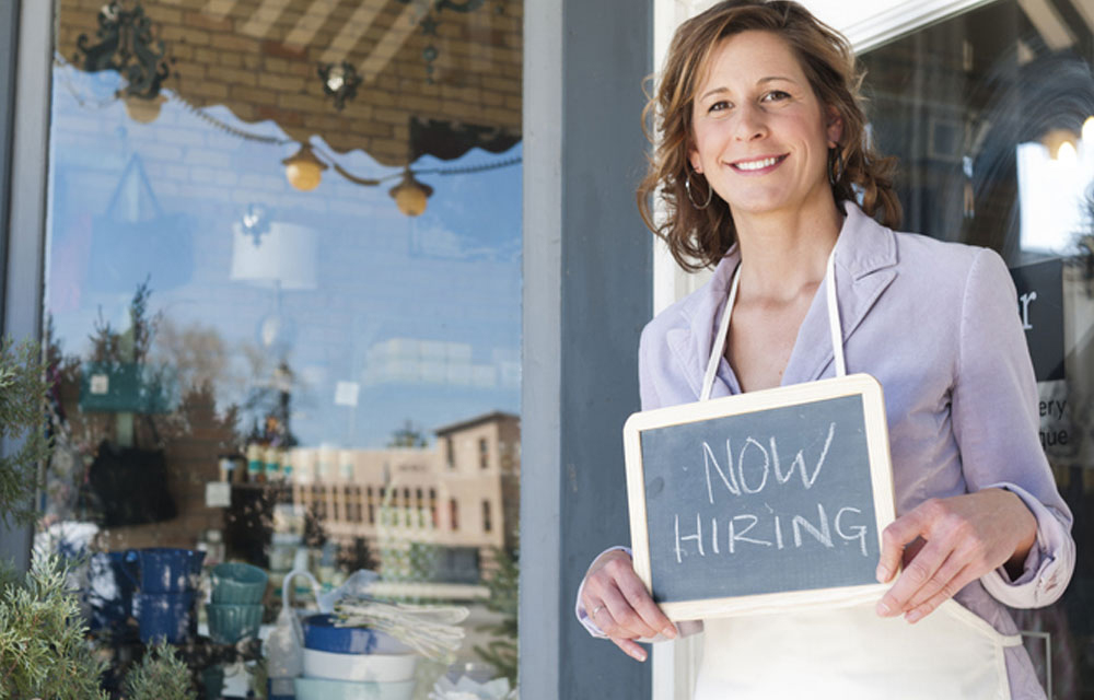 Now Hiring sign being held by woman