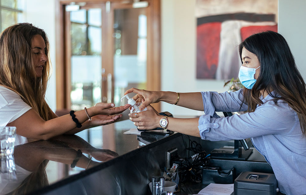 Two women using hand sanitizer in a business