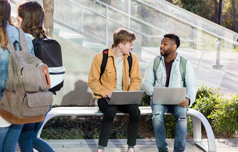 two guys chatting with their laptops open