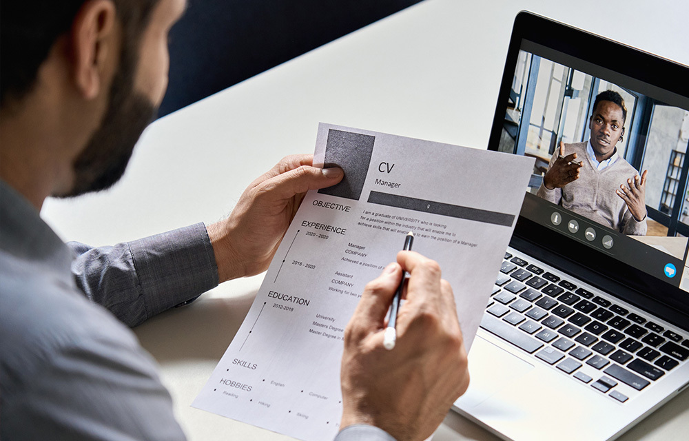 man sitting in front of laptop with his resume in hand