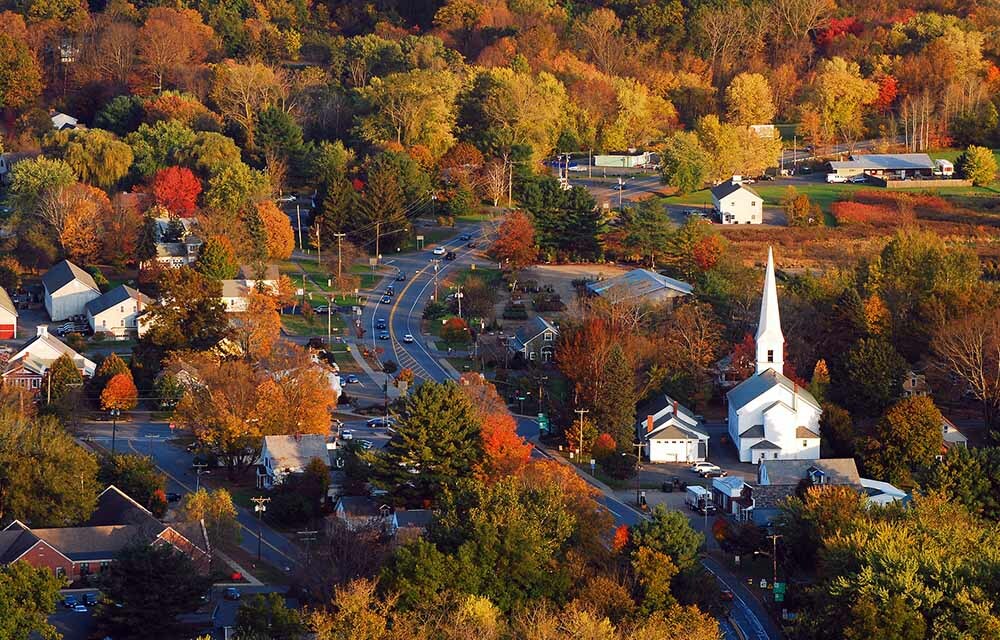 Scene with church peeking out of a large amount of trees