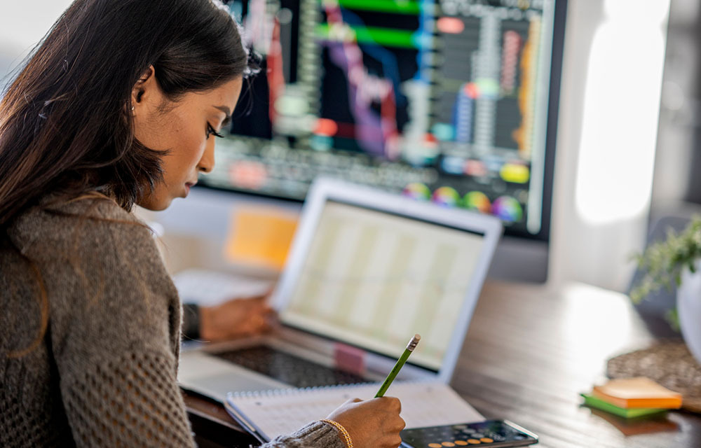 Young woman doing finances from her dining room table.