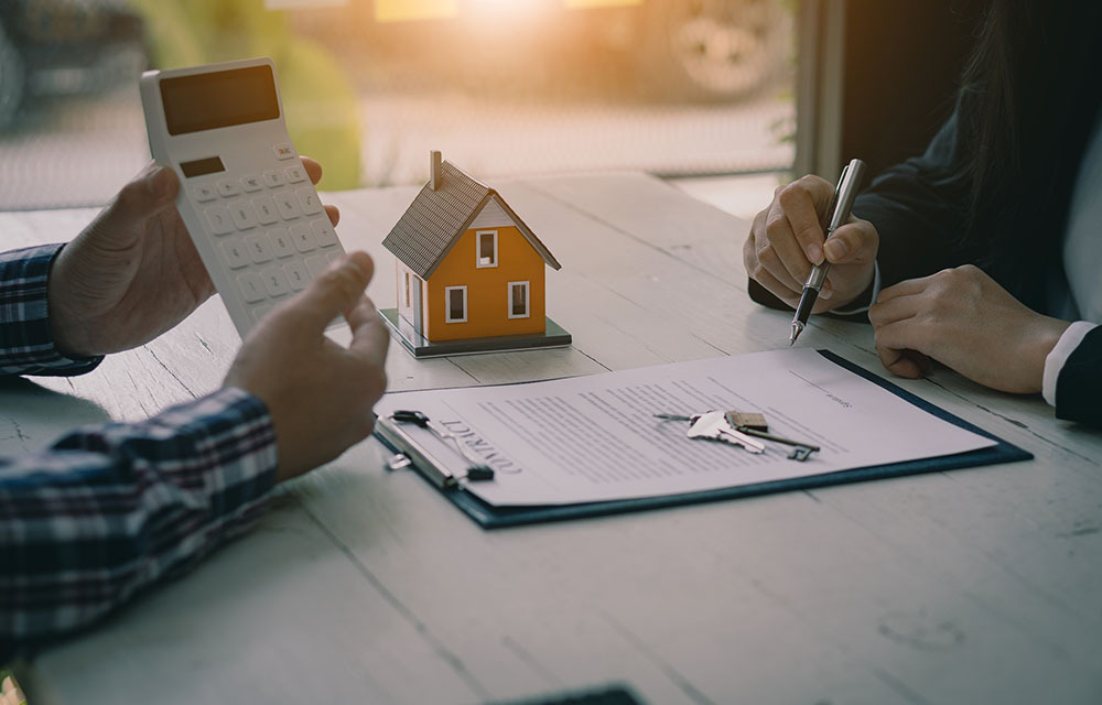 Man showing calculator results while analyzing housing market on paper