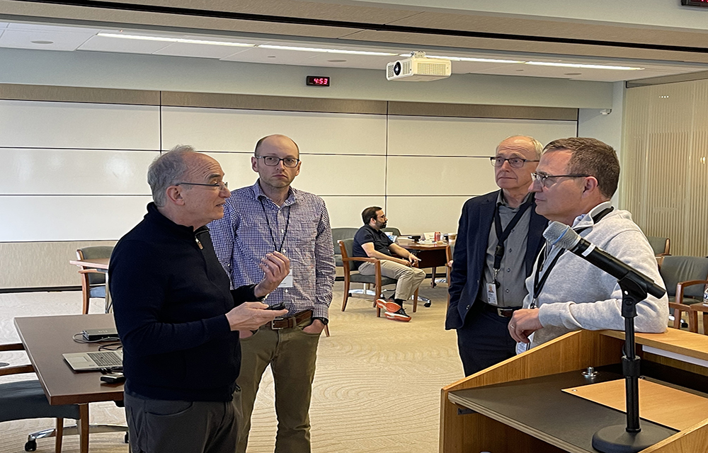 Group of economists standing in circle and talking.