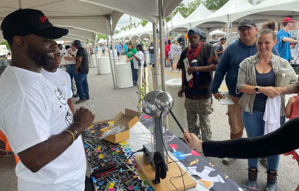 Curious participants interacting with a science project being shown by Steven DK Brown.