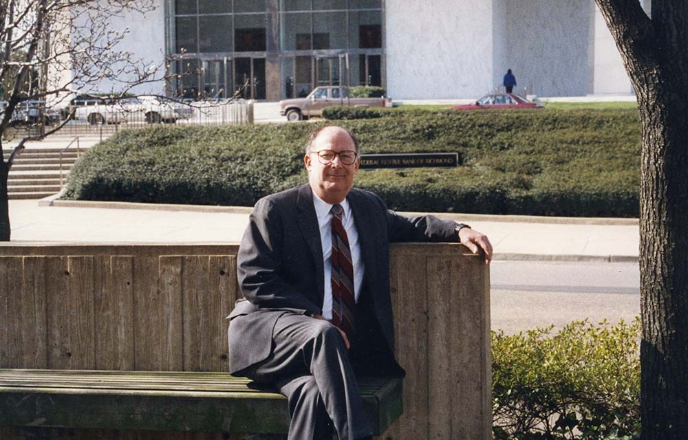 Al Broaddus sitting on a bench outside of the Richmond Fed building.