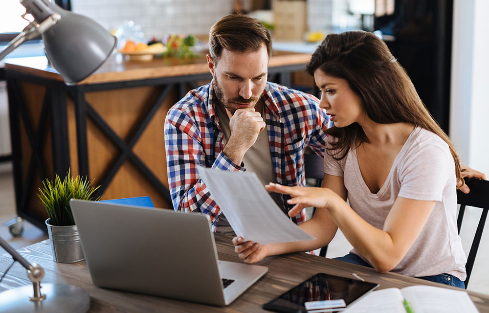 a couple reviews their finances at a laptop