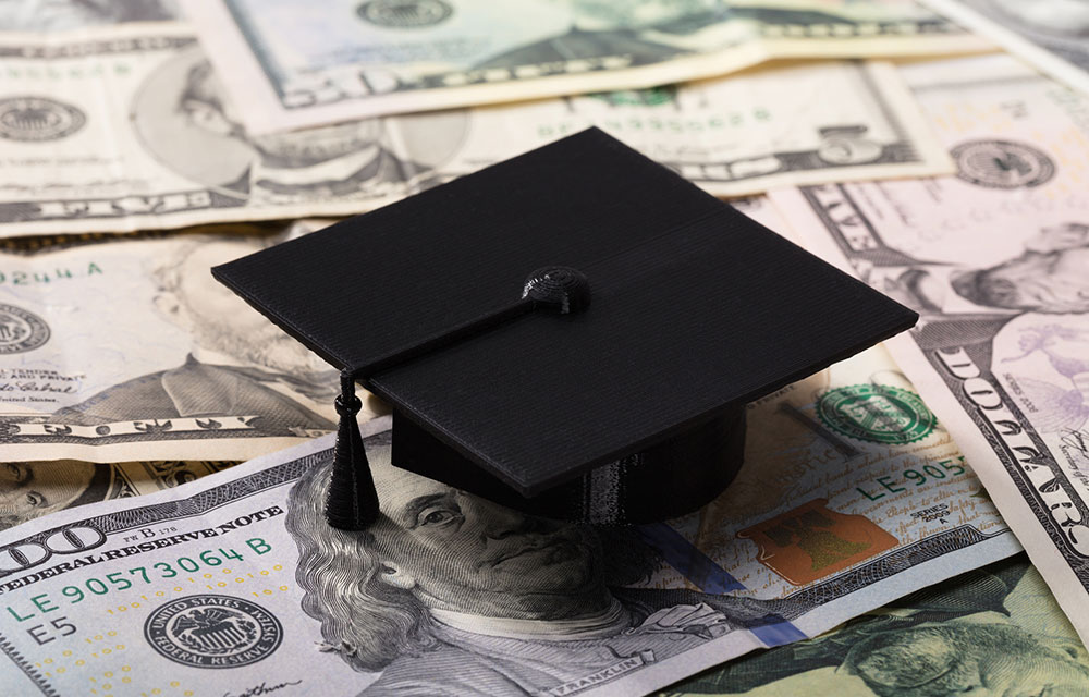 graduation cap on a pile of money