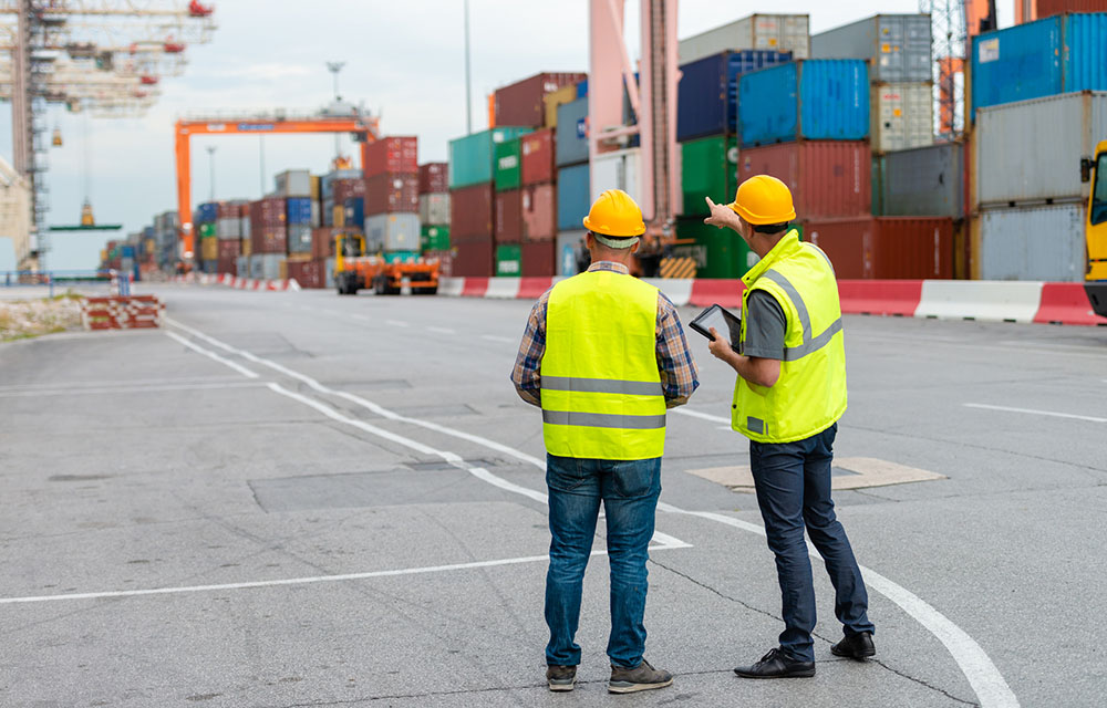 Men supervising movement of containers at port