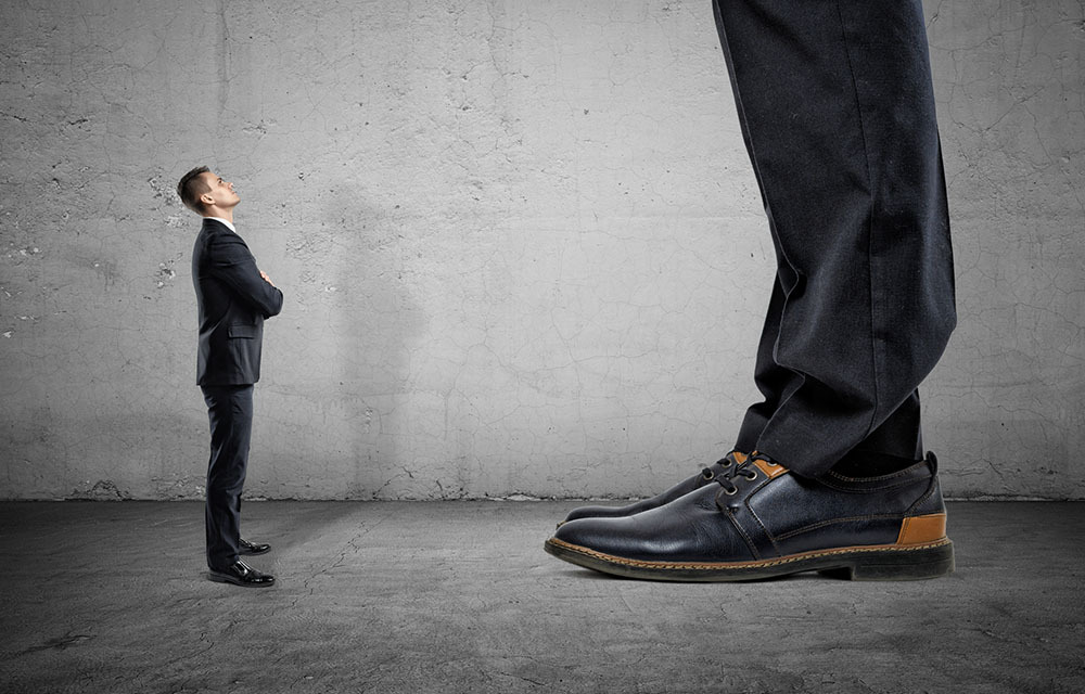 small man in suit looking up at giant man