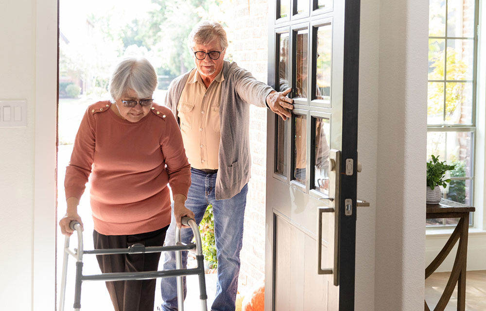 Older couple carefully stepping inside their home.