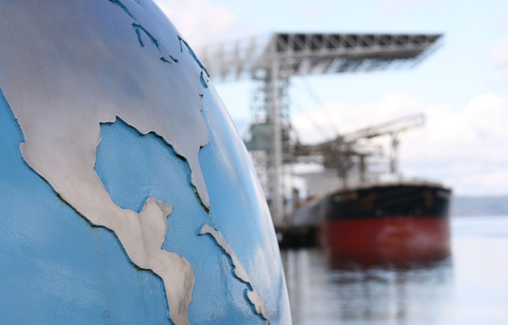 Globe in foreground and container ship in background