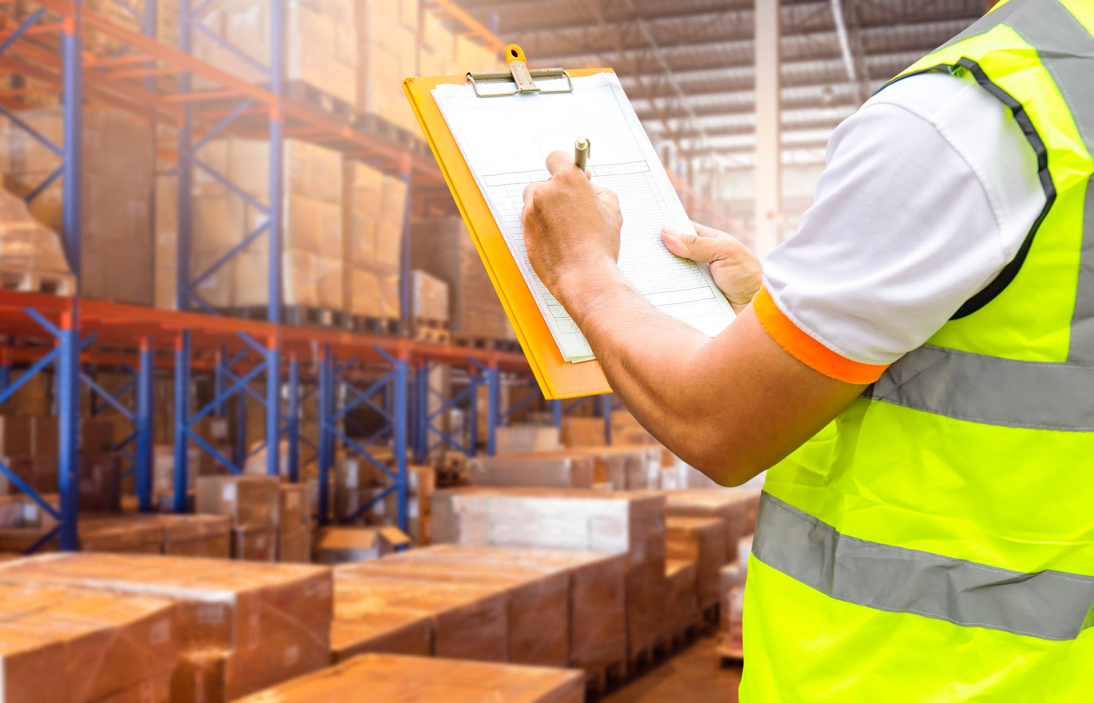 Person with clipboard checking inventories in a warehouse