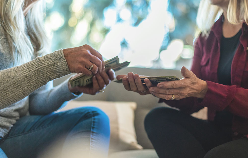 A woman handing another woman money