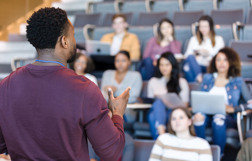 man addresses a group of students at college