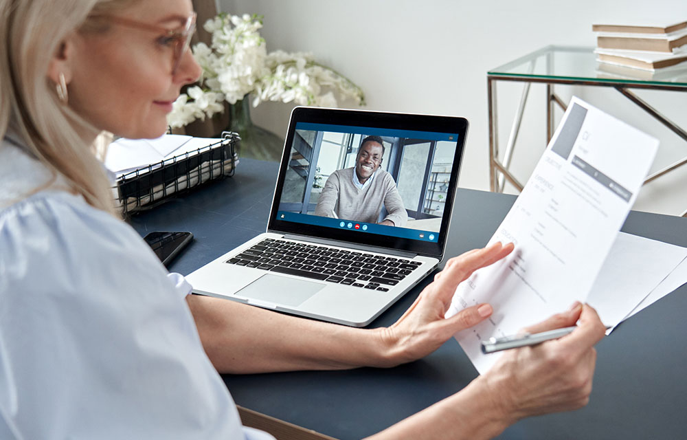 Image of woman looking at resume while in a virtual interview.