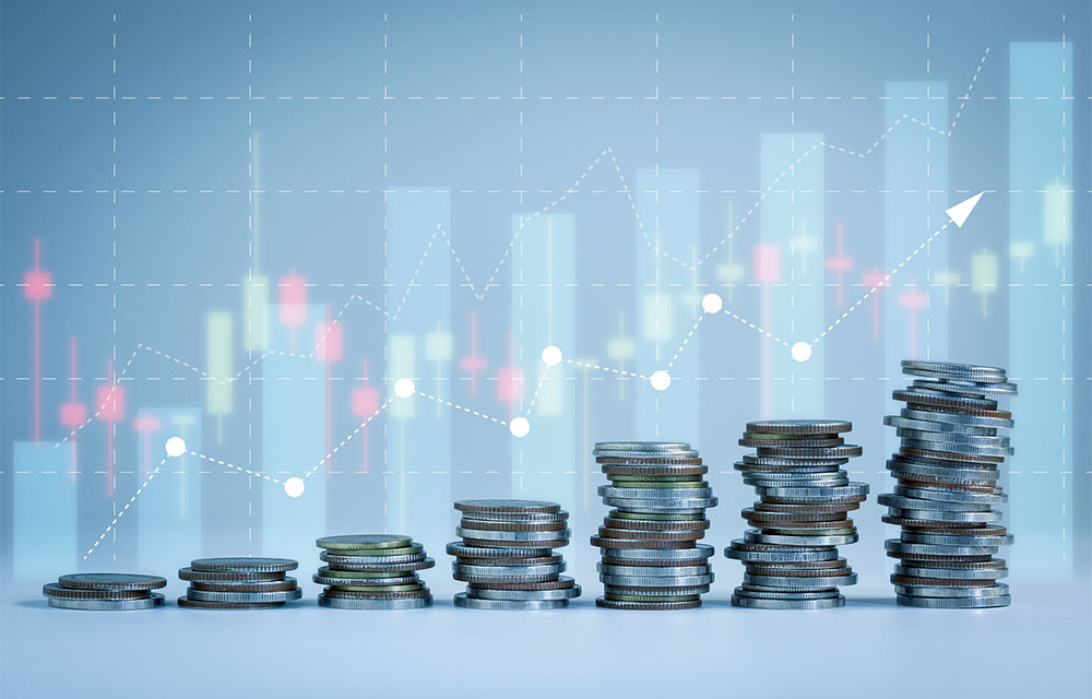 Stacks of coins increasing in a step like-manner with graphical charts in the background showing an upward trend.