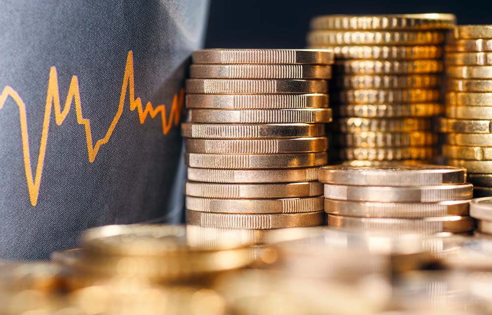 Stack of coins with a curve of fluctuating prices of financial markets.