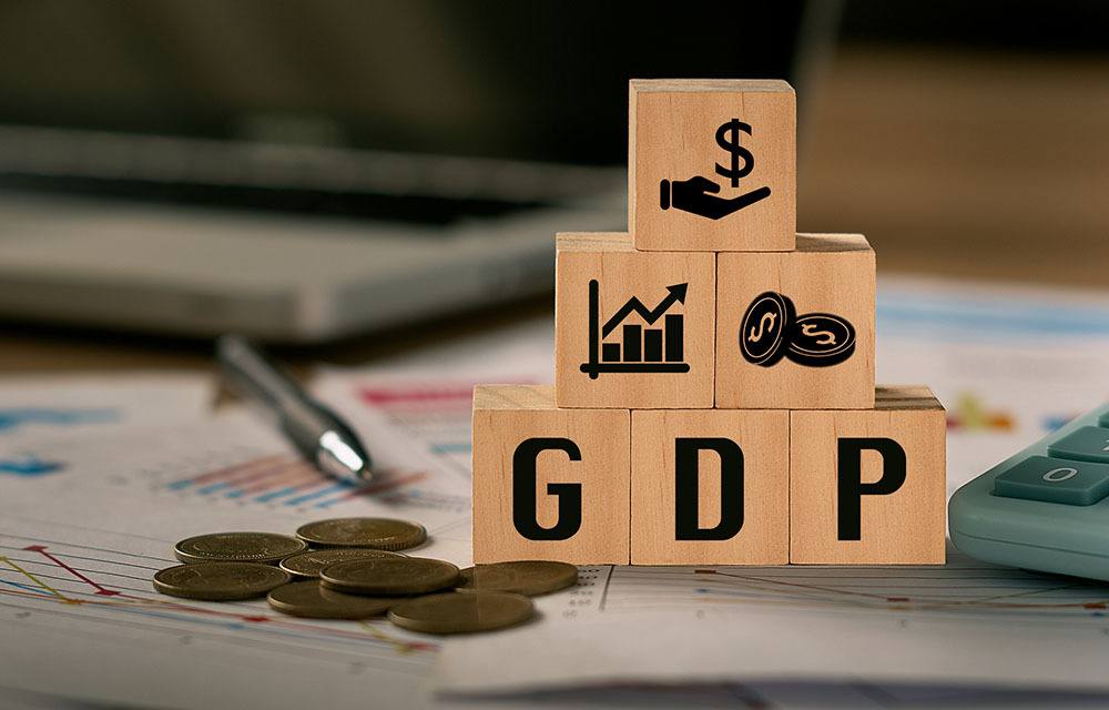 Stack of blocks with "GDP" written out and blocks with economic symbols like a chart and coins.
