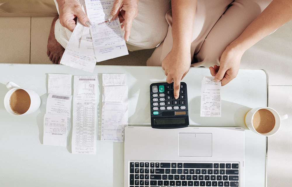 Daughter using calculator, computer, and receipts to help mother with home finances.