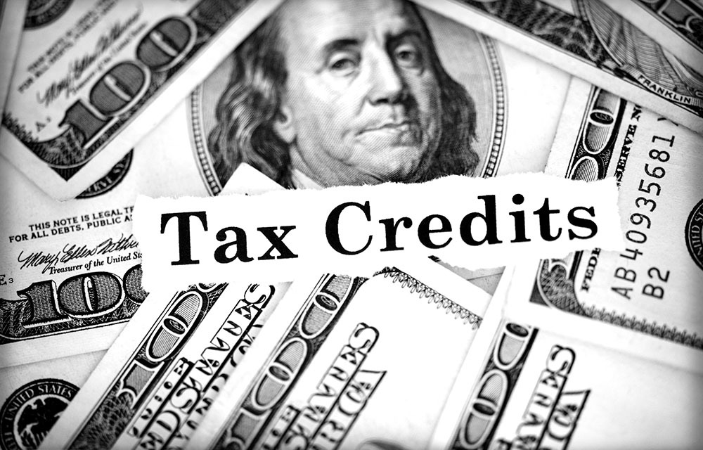 Assortment of hundred-dollar bills with a label laying on top that reads "tax credits."
