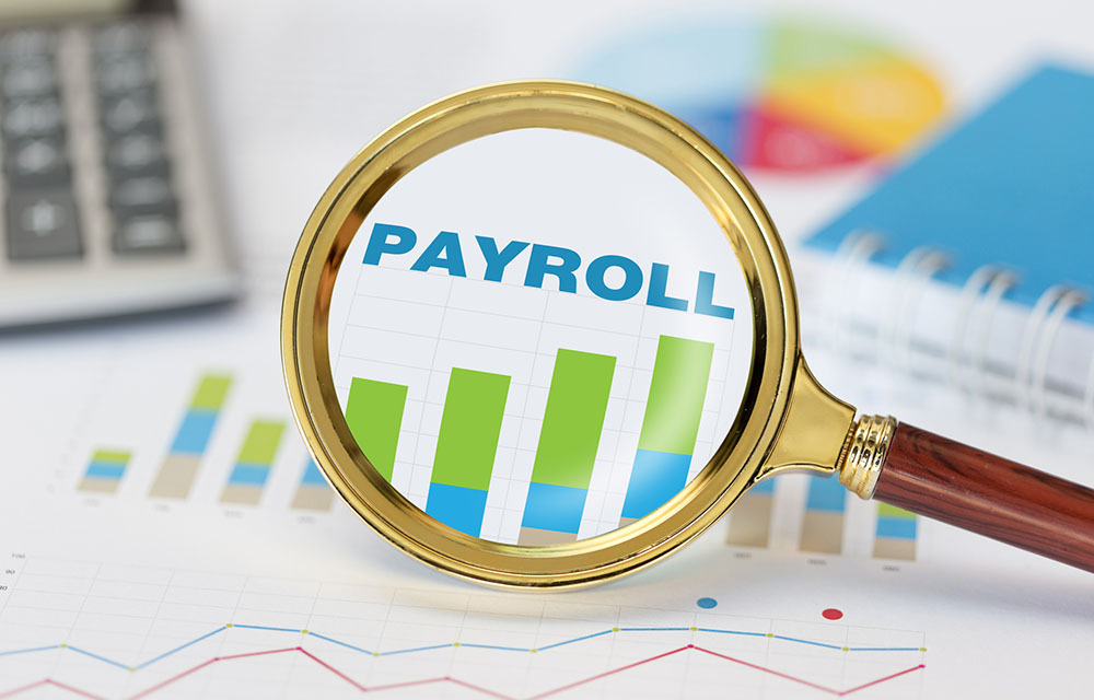 Magnifying glass focused on a payroll chart.