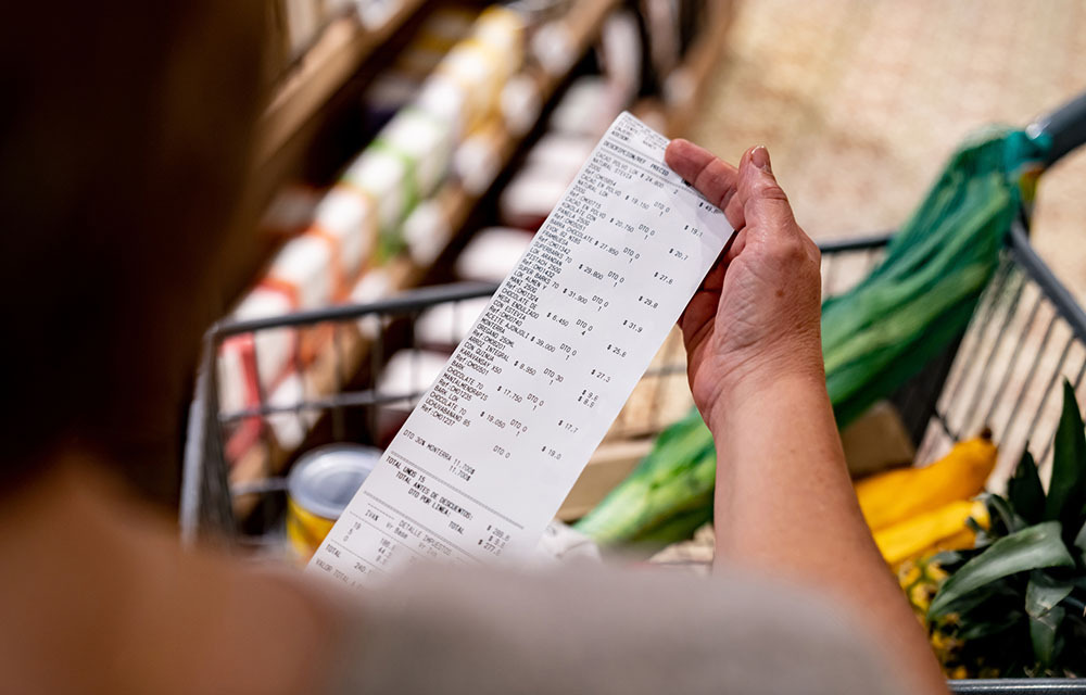 Person looking at a long receipt after shopping at the grocery store.