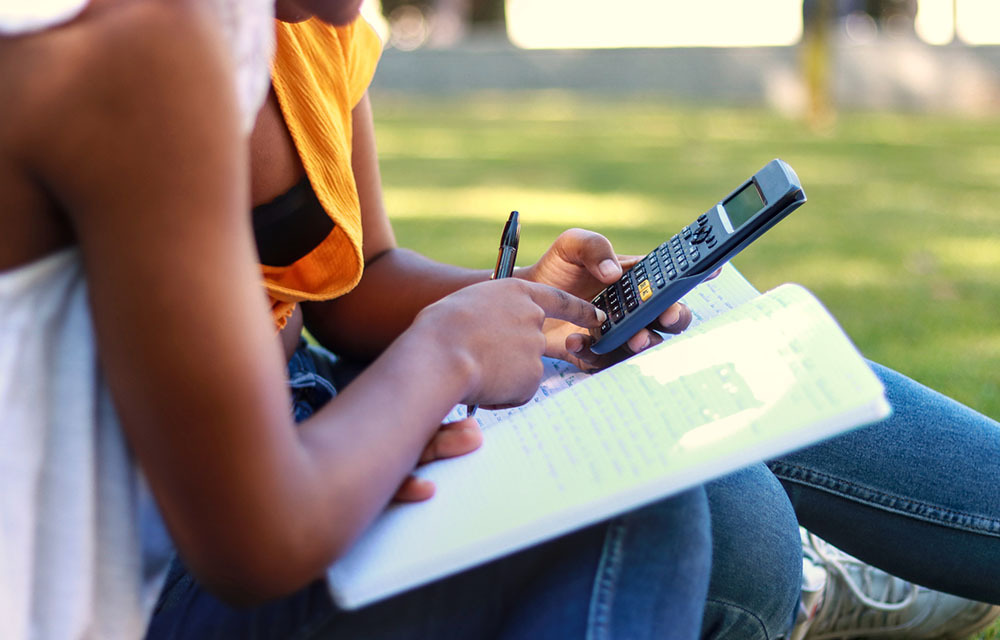 College students using a calculator and working on an assignment together.