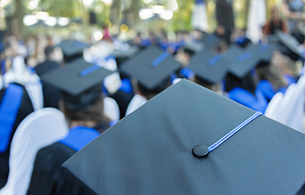 Image of graduates turned away with their graduation caps and tassels in display.