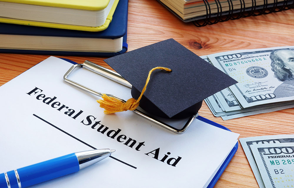 Federal student aid application with a small graduation cap sitting on top.