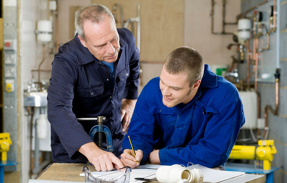 Plumbing instructor checking his apprentice's written work.