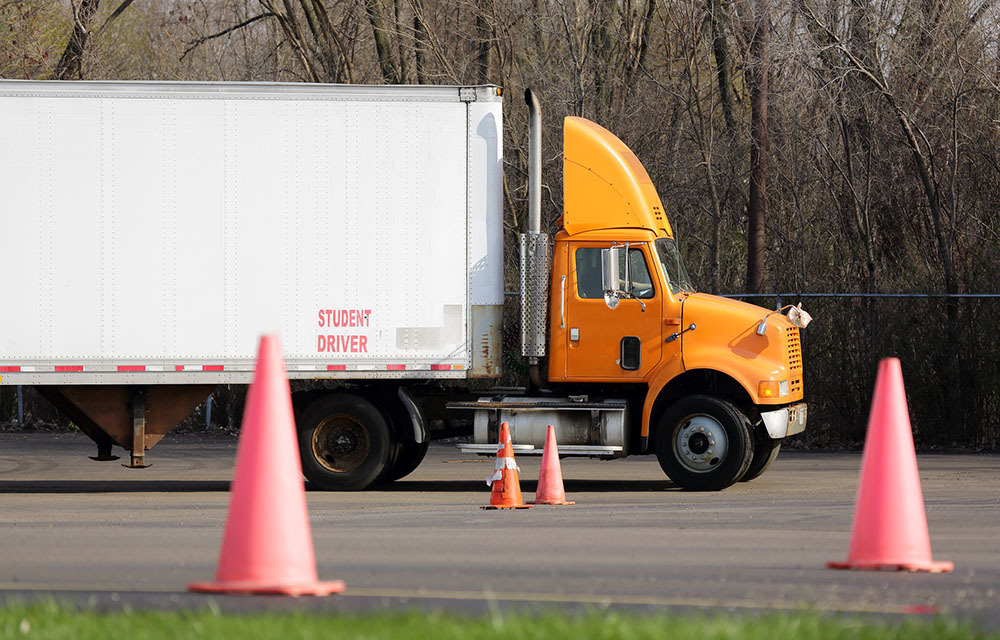 Student semi-truck driver maneuvering cones to practice parking.