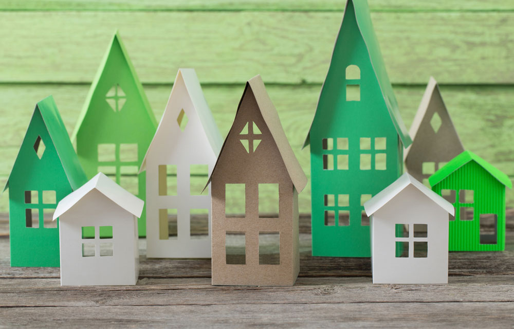 Row of houses crafted with paper on a wooden table.