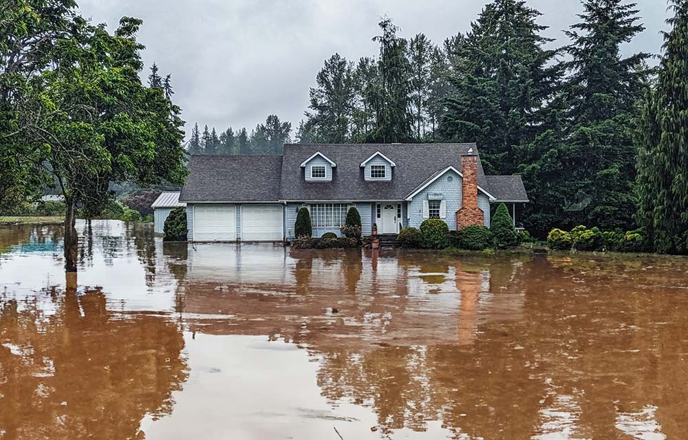 Exterior of a house with a yard flooded by muddy water.
