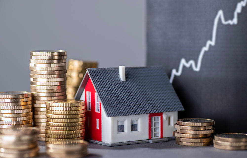 House with stacks of money and a rising curve symbolizing rising real estate prices.